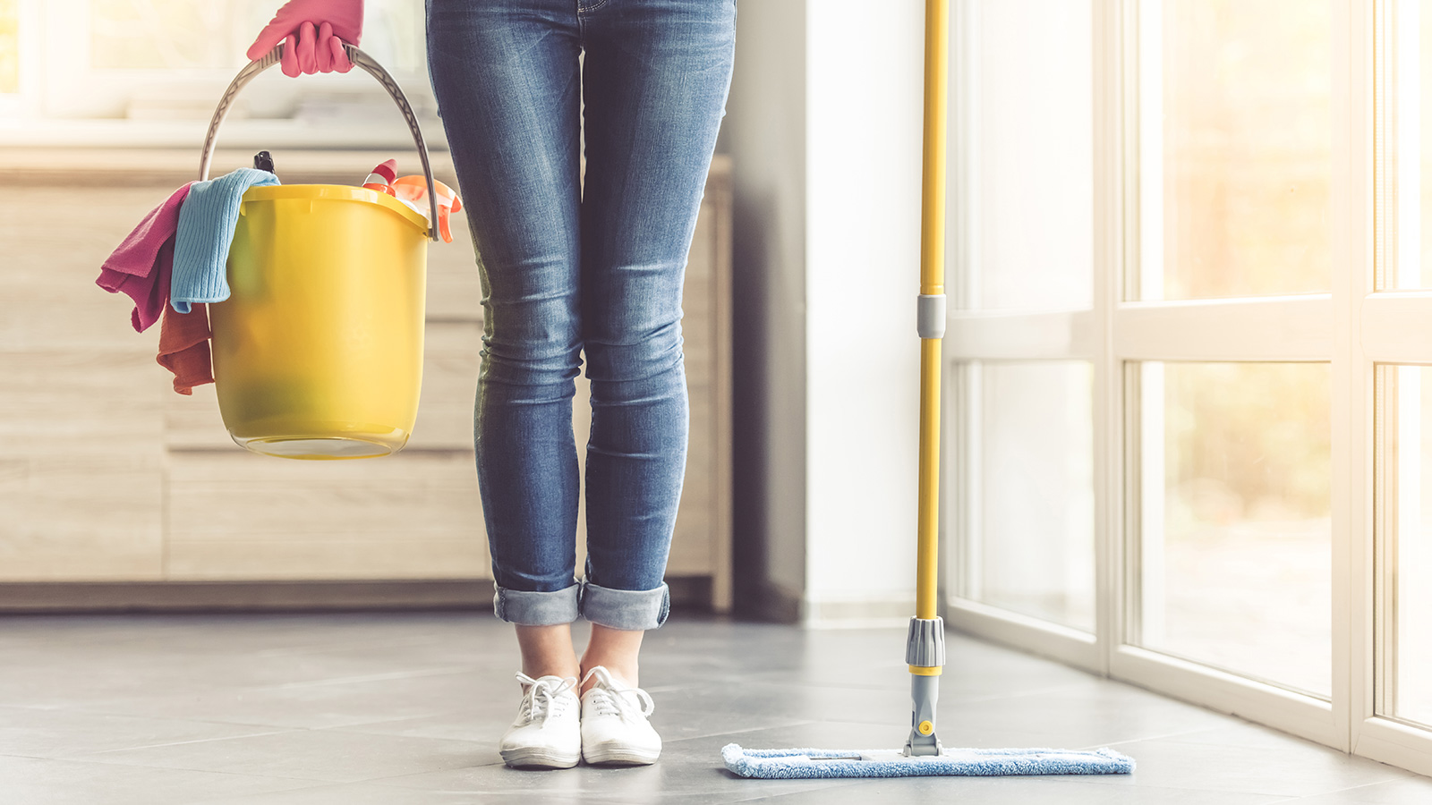 donna con in mano secchio con prodotti per le pulizie